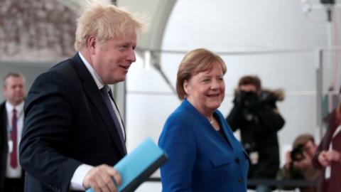 Boris Johnson is greeted by Angela Merkel as he arrives in Berlin for a summit about Libya, in January 2020
