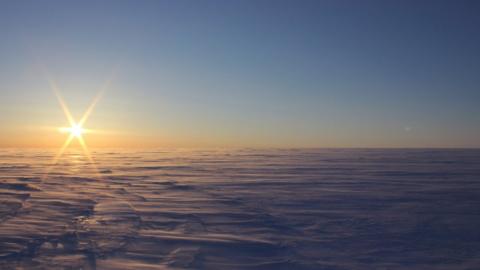 The sun over a windswept ice field