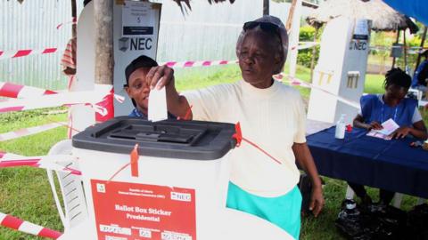 A woman and child dropping a vote in the ballot box