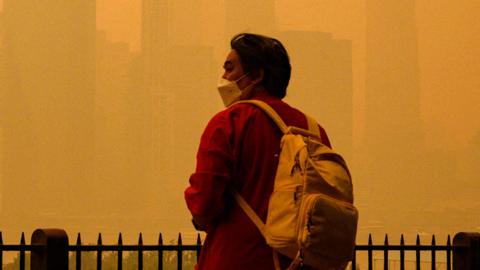 A person wears a face mask as smoke from wildfires in Canada cause hazy conditions in New York City on June 7, 2023