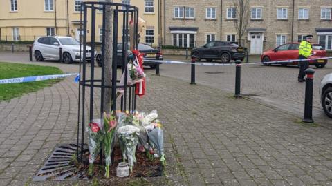 Flowers tied to railings and police tape in Swindon