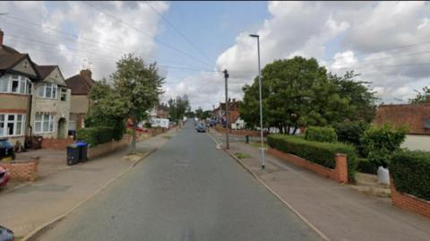 Wide road with houses and trees either side