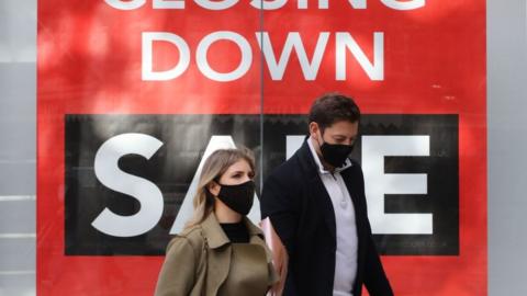 Couple walk past closing down sale sign