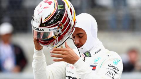 Lewis Hamilton takes of his crash helmet