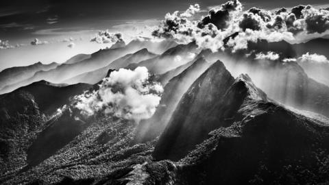 Black and white photograph of a cloud above mountains