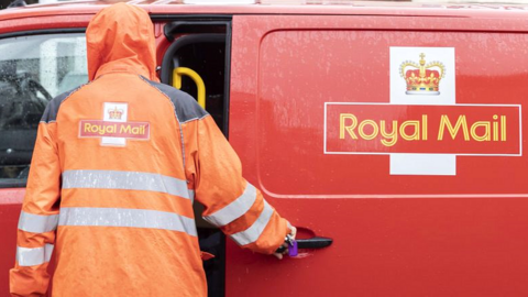 Royal Mail worker wearing an orange jacket opening a royal mail van door