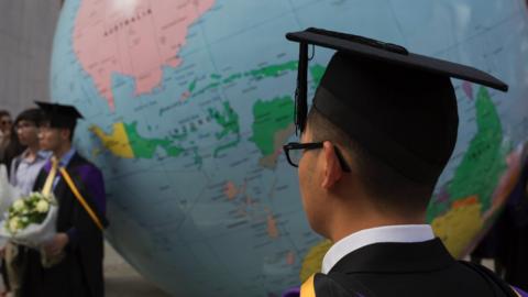 A student stands infront of a giant globe