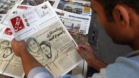 Man looks at newspaper with drawing of arrested journalists Elaheh Mohammadi and Niloufar Hamedi (30/10/22)