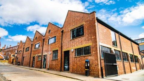 Old brick warehouse with pointed roofs refurbished as a modern business centre