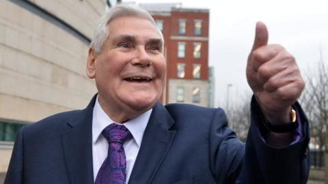 Pastor James McConnell gives a thumbs-up gesture to supporters outside Laganside Court in Belfast