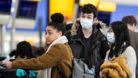 Young people wearing masks while queuing at a UK airport