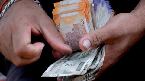 A fruit vendor counts a wad of Indian Rupee currency notes for payment at his roadside stall in Mumbai on July 19, 2022.