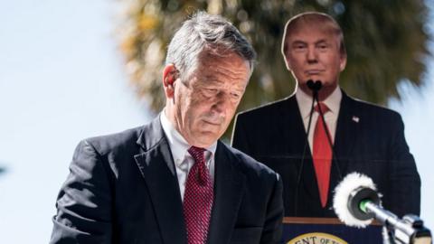 Former South Carolina Gov. Mark Sanford takes the podium before speaking to the media with a cardboard cutout of President Donald Trump during a campaign stop