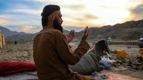 An Afghan refugee man performs an evening prayer in a temporary shelter upon his return to his homeland through the Afghanistan-Pakistan border at Torkham.