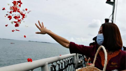 Woman throwing flowers into the sea