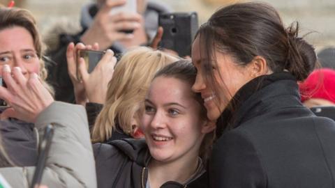 Meghan Markle poses for a photograph with a fan