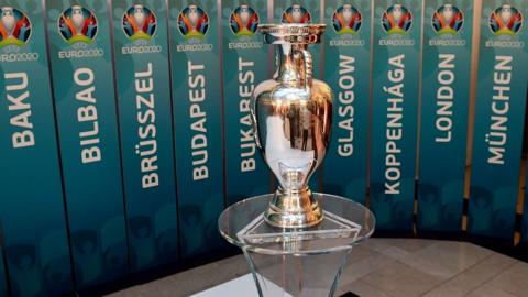 A model of the UEFA European football championship trophy in front of names of host cities