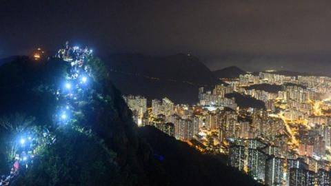 People light up mobile phones on Lion Rock above Hong Kong as part of a human chain of protest