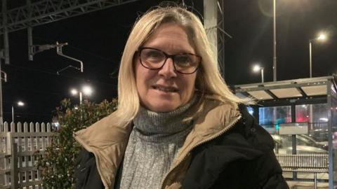 Woman with blond hair and glasses at a railway station