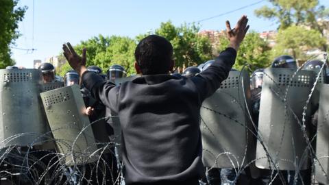 A protester holds up his hands in front of a police barricade in the Armenia capital of Yerevan
