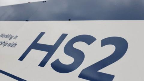 A HS2 high-speed rail logo is displayed on a fence