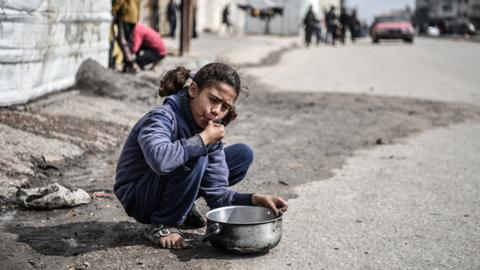 A Palestinian girl feeds herself with distributed food in Rafah city, Gaza