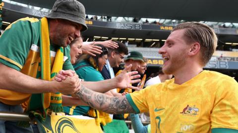 Australia striker Jason Cummings celebrates with a fan