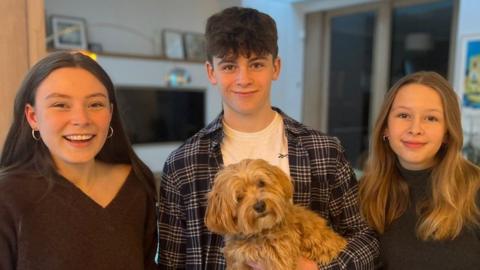 Left to right: John Hume's grandchildren Isabel, Ollie and Rachel holding a dog