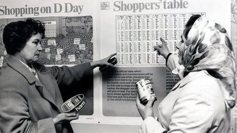 Two women looking at a conversion chart for their money