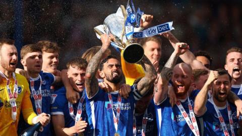 Portsmouth players celebrate their title triumph by lifting the League One trophy