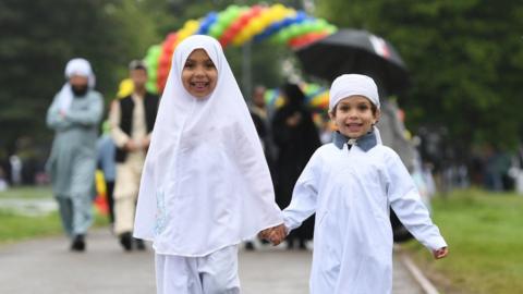 Muhammad, four, and Sanaa, six, (left) arrive for the Eid celebrations in Small Heath Park, Birmingham