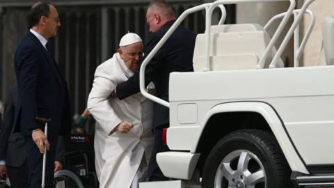 Pope Francis is helped get up the popemobile car as he leaves on March 29, 2023 at the end of the weekly general audience at St. Peter's square in The Vatican