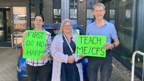 Three protestors holding green neon signs saying First Do No Harm and Teach ME/CFS