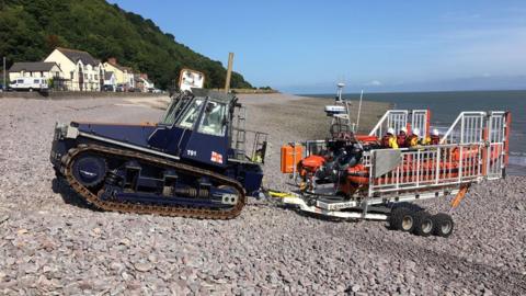 Lifeboat on trailer being towed by tractor on the beach