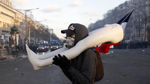 Protester carries broken mannequin on Champs-Elysées, 16 Mar 19