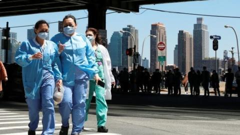 Healthcare workers from the NYU Langone Medical Center walk away after watching the U.S. Navy Blue Angels and U.S. Air Force Thunderbirds demonstration teams participate in a midday flyover of the New York City region as part of the "America Strong" tour of U.S. cities to honour first responders and essential workers during the outbreak of the coronavirus disease (COVID-19) in the U.S., April 28