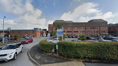 View of Scunthorpe General Hospital with car park and hedge in the foreground