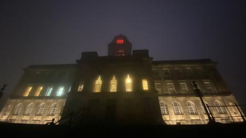 An illuminated Wallasey Town Hall, seen at night from the banks of the River Mersey.