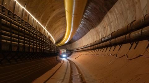 A photo showing the inside of a tunnel built as part of HS2. A machine with a light on is visible in the tunnel.