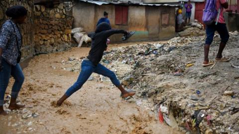 People cross a flooded street in Haiti, after Hurricane Melissa caused flooding on the island.