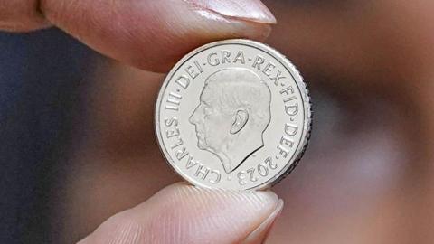 finger and thumb hold the new 5p coin showing king charles iii in profile