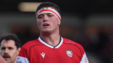 Freddie Thomas standing on the pitch wearing Gloucester kit and head tape during a match in October 2025 