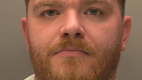 Police custody photograph of Stuart Wells who has dark short hair and beard 