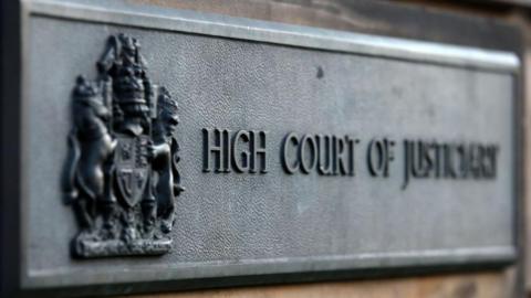 Grey sign outside High Court in Edinburgh which reads High Court of Justiciary.