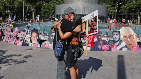 People embrace near a fountain turned to a memorial in Tel Aviv for Israelis killed during and in the two years since the 2023 attacks by Palestinian militants, and those who remain hostages in Gaza, on the second anniversary of the attacks on October 7, 2025