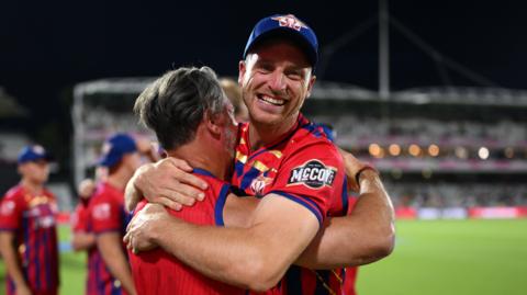 Manchester Super Giants captain Jos Buttler smiles as he embraces a member of the coaching staff after winning the 2026 men's Hundred title