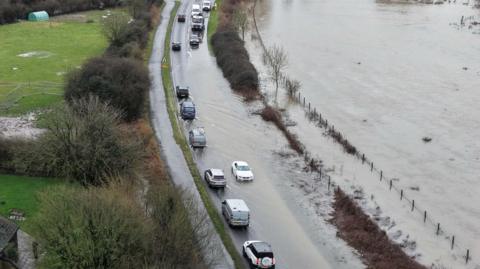 Vehicles on a road that is flood due to storm Chandra and the heavy rain last week.