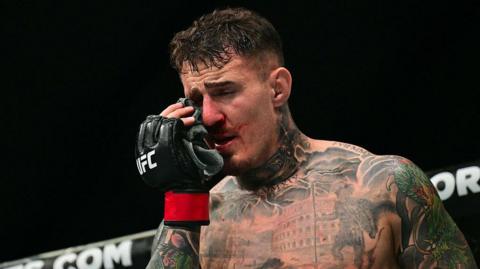 UFC heavyweight champion Tom Aspinall touches his eye after being poked by Ciryl Gane at UFC 321