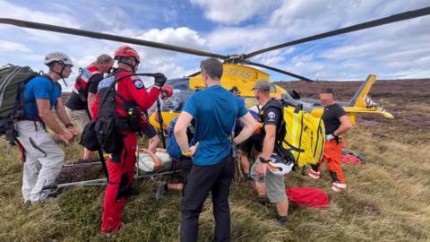 Edale Mountain Rescue Team helps a runner on a stretcher on to an air ambulance in the southern edges of Kinder in Derbyshire.