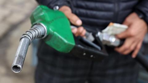 A man holding a green petrol pump 